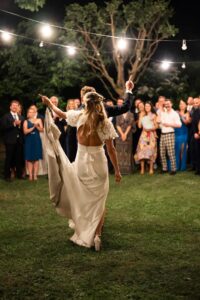 Bride and groom dancing with raised arms in front of their guests
