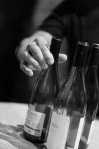 Black and white photo of a hand holding a wine bottle during a tasting
