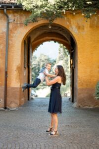 Young woman catching a boy after tossing him into the air in front of a stone archway