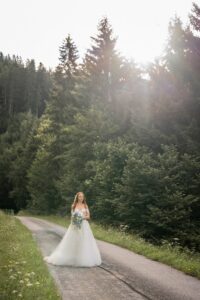 Vintage photo of a bride walking toward her groom while sunlight shines through the trees