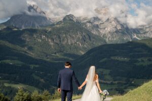 Wedding couple walking hand in hand along a path toward the mountains