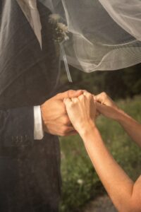 Close-up beneath the veil of a wedding couple holding hands