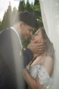 Vintage grainy photo of a groom holding his bride’s face while leaning in for a kiss