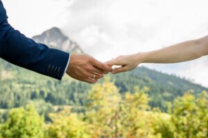 Wedding couple holding hands in front of the mountains