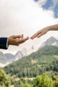 Close-up of hands almost touching in front of mountain scenery and sky