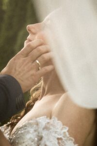 Close-up beneath the veil with the bride looking lovingly at her groom while he touches her face