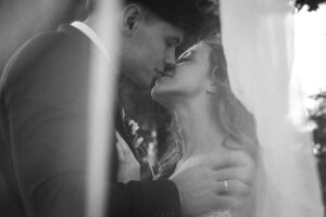 Vintage black-and-white photo of a wedding couple kissing beneath the veil