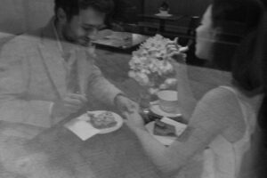 Vintage cinematic black-and-white photo of a wedding couple eating cake in a café
