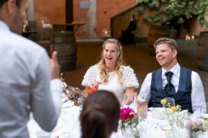 Bride and groom laughing during the speech given by their wedding attendants