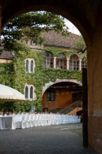 White reception table in the castle courtyard photographed through an archway