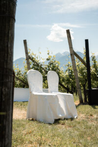 Two white ceremony chairs placed among the vineyards