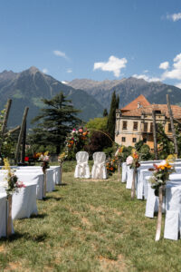 Outdoor wedding ceremony setup at Schloss Rametz in South Tyrol overlooking vineyards, mountains, and the castle