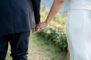 Close-up of a bride and groom holding hands lovingly