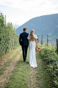 Bride and groom walking hand in hand through nature while looking into the landscape
