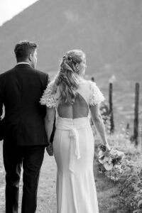 Black and white photo of a bride and groom holding hands while looking out into nature