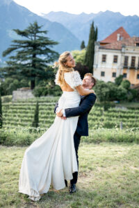 Groom lifting his bride and spinning with her in front of the South Tyrolean landscape