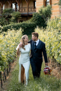 Bride and groom walking arm in arm through the vineyard rows of a South Tyrolean winery
