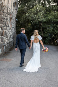 Bride and groom walking hand in hand through the vineyards of South Tyrol