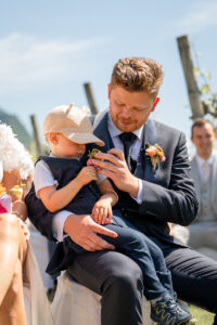 The groom holds his son on his lap and looks at him