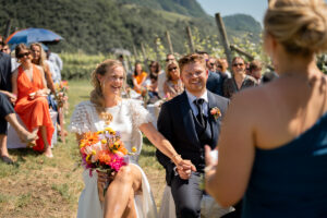 The wedding couple sits hand in hand during the ceremony