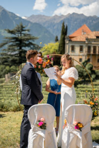 The bride reads her vows to the groom with Schloss Rametz and the mountains in the background