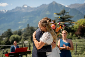 Intimate embrace of the wedding couple during the ceremony with the mountains behind them