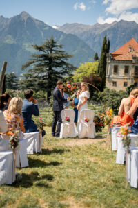 The wedding couple stands and reads their vows to one another with Schloss Rametz and the mountains behind them