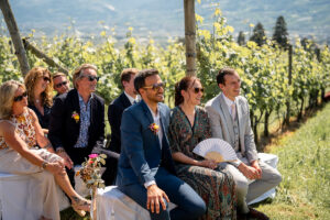 Happy wedding guests standing in front of the vineyards