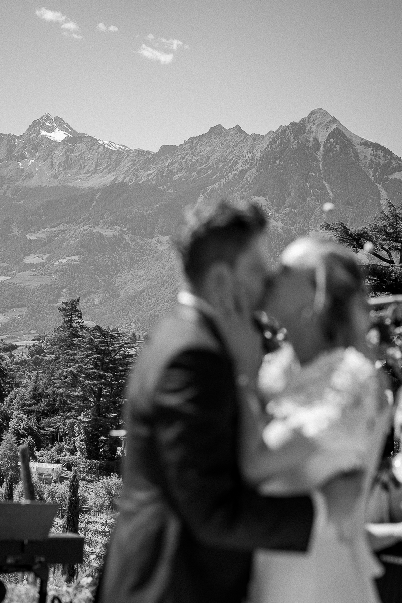 Soft-focus black-and-white photo of a wedding kiss in front of the South Tyrolean mountains