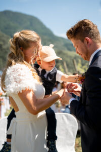 The groom places the ring on his bride's finger while she holds their child