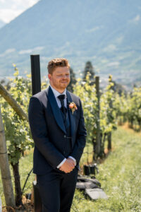 The groom stands beside the vineyards and sees his bride for the first time