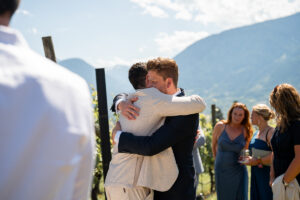 The groom is hugged by a guest and closes his eyes