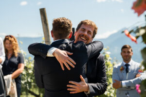 Warm embrace between the groom and a laughing guest