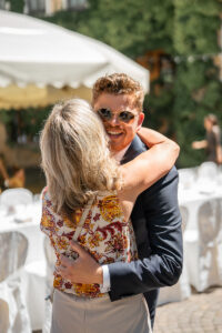 The groom hugs a woman while laughing warmly