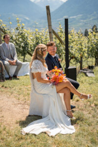 Bride and groom sit among the vineyards during the ceremony and talk to each other