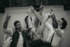 Black-and-white photo of the dance floor with raised hands and focus on the wedding couple