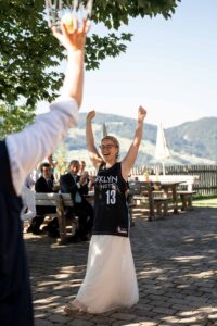 Bride throwing a tennis ball into a basket during a wedding game