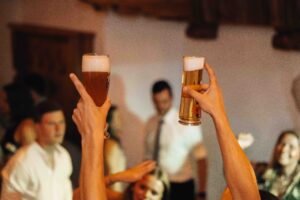 Detail photo of hands holding two beer glasses in the air