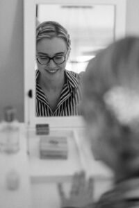 Black-and-white photo of the bride in the mirror looking at her nails