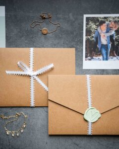 Close-up flat lay of envelopes, jewelry, and a photo of the couple