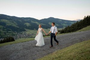 Wide-angle photo of the wedding couple walking with mountain views