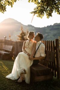 Bride sitting on her groom’s lap at sunset