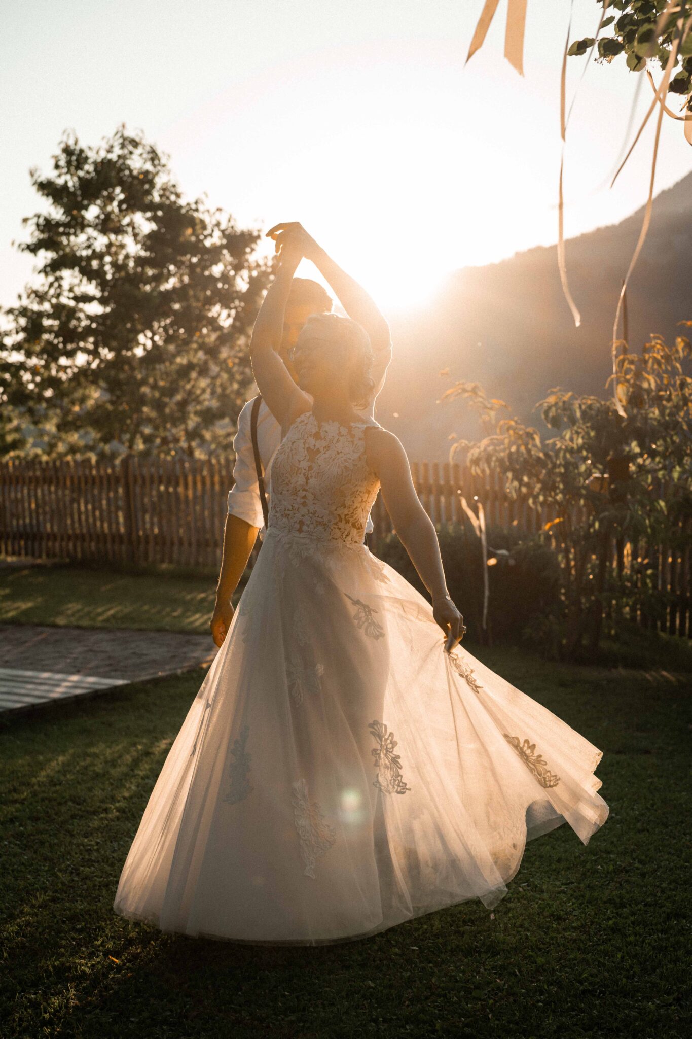 Bride twirling in the wind at sunset in front of her groom
