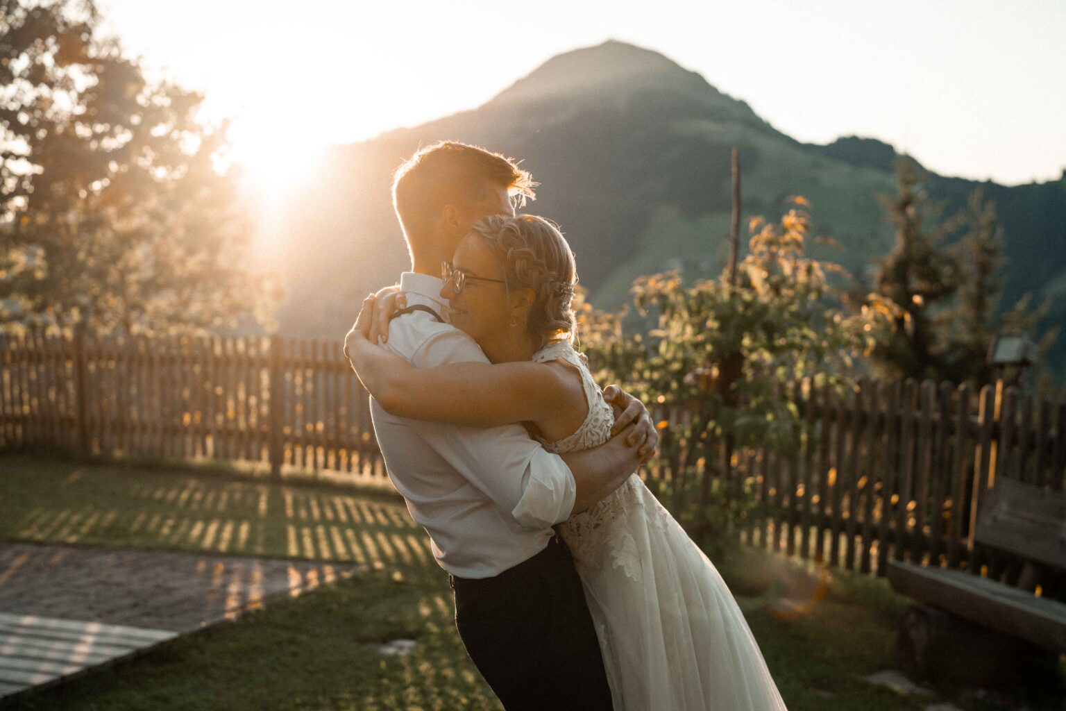 Bride joyfully falling into her groom’s arms at sunset
