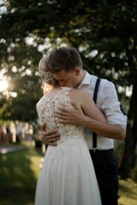 Intimate embrace of the wedding couple beneath sunlit trees