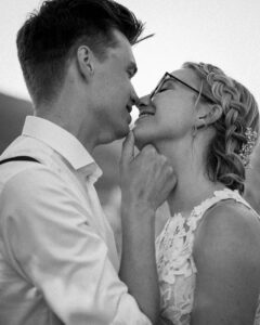 Black-and-white detail photo of the groom holding his bride’s chin