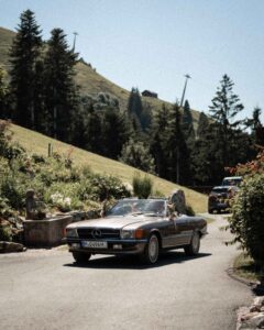 Vintage cinematic photo of the wedding couple arriving in a vintage car