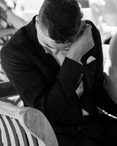 Black-and-white photo of a groom wiping away tears