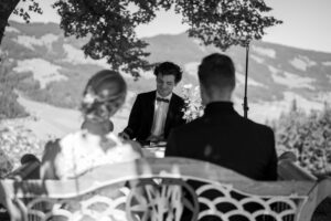 Black-and-white photo of the officiant framed between the couple’s heads