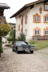 A vintage Cadillac drives through an Austrian village on the way to the church